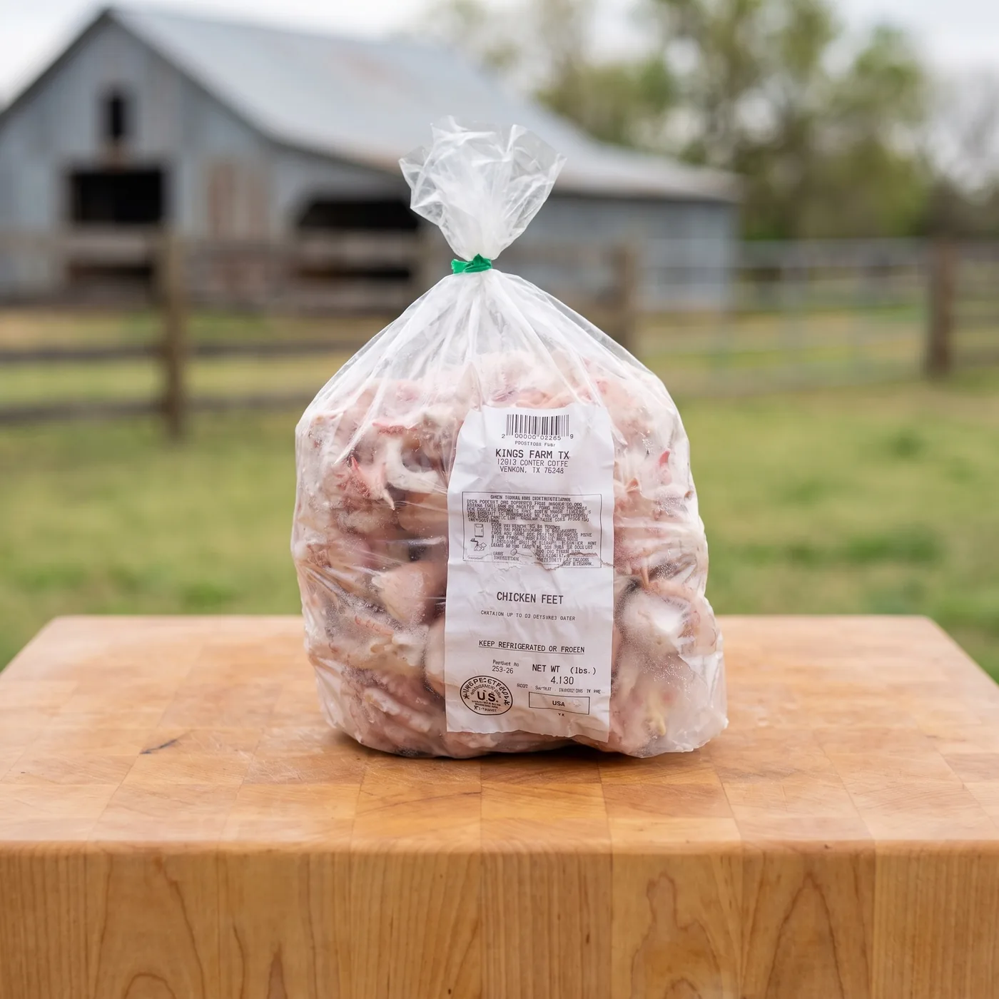 A tied bag of cleaned Kings Farm TX chicken feet on a butcher block, the barn and pasture behind.