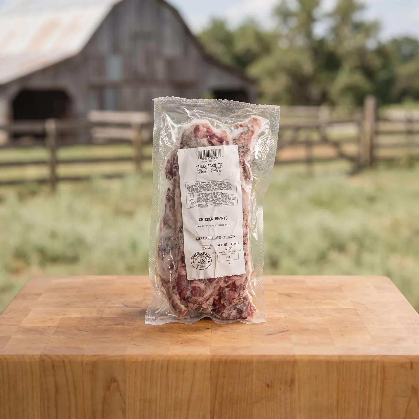 A sealed pack of Kings Farm TX chicken hearts on a butcher block, the barn and pasture behind.