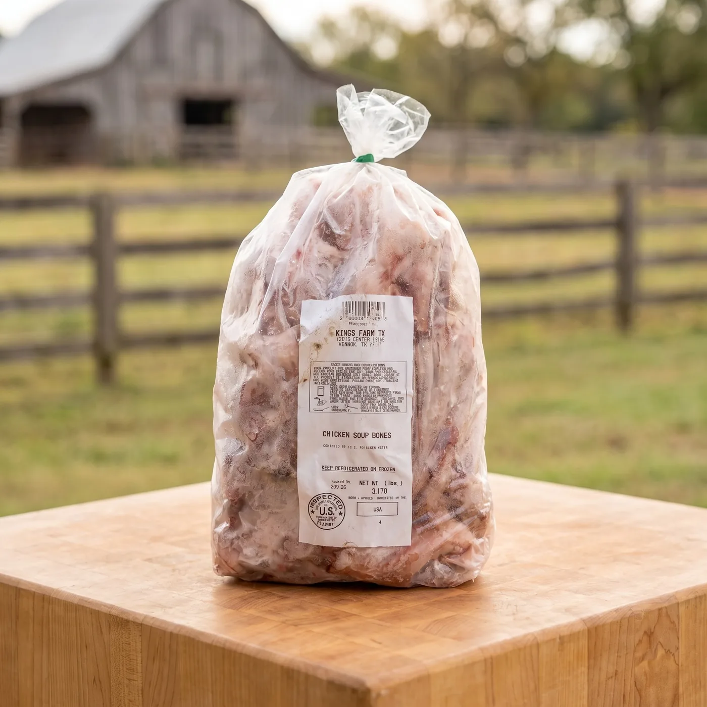 A tied bag of Kings Farm TX chicken soup bones on a butcher block, the barn and pasture behind.