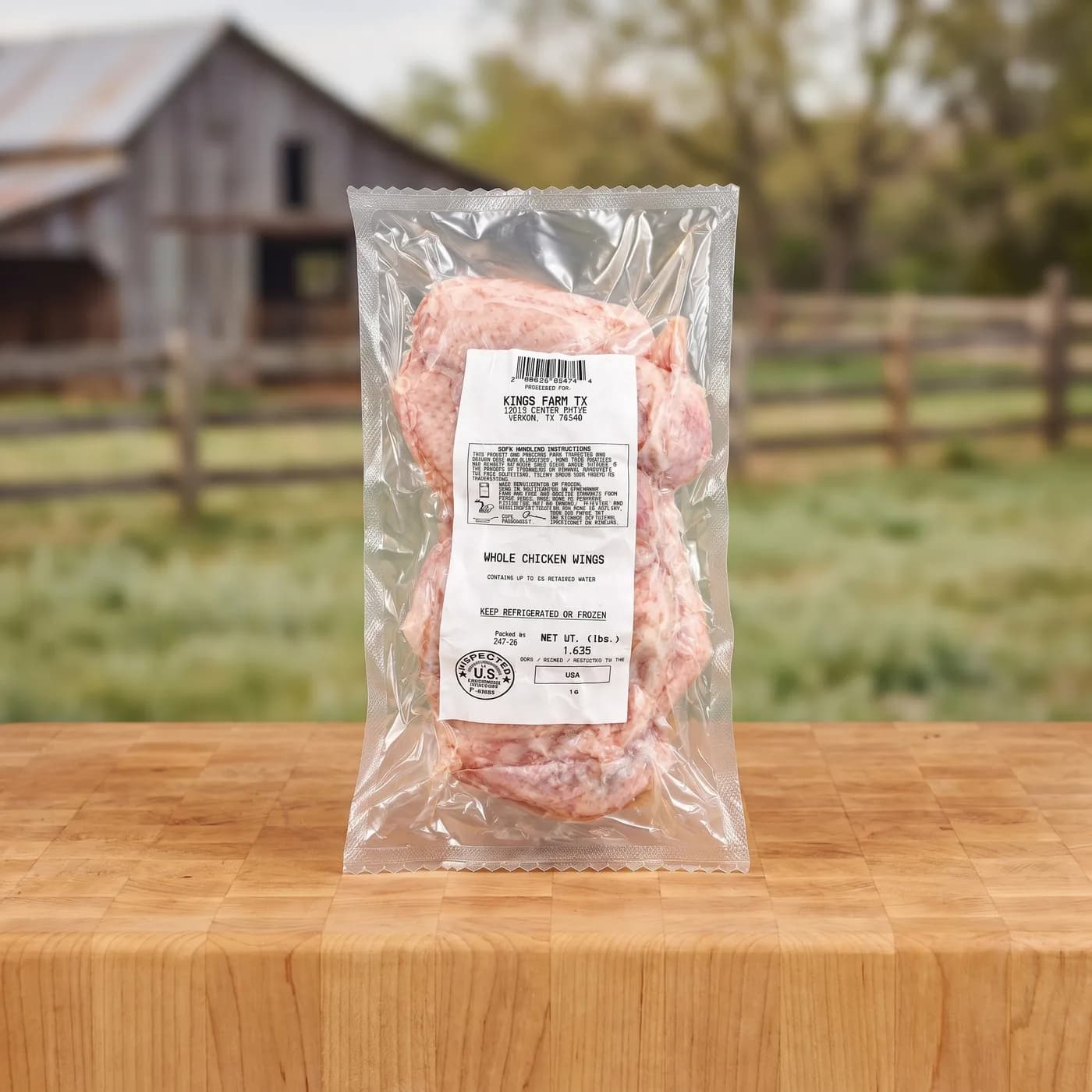A sealed pack of Kings Farm TX whole chicken wings on a butcher block, the barn and pasture behind.